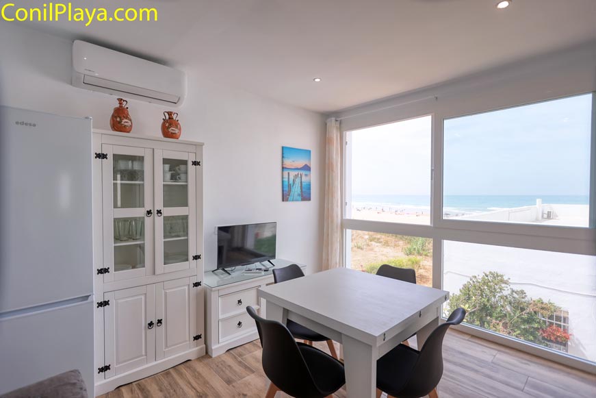 Comedor moderno con mesa blanca y grandes ventanales con vistas a la playa