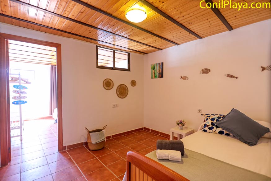 Vista desde la puerta del dormitorio con cama individual decorado con motivos marinos y techo de madera