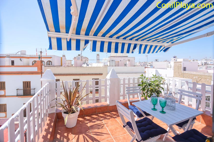 Vista de la terraza con mesa sillas y toldo azul ideal para cenas viendo la puesta de sol