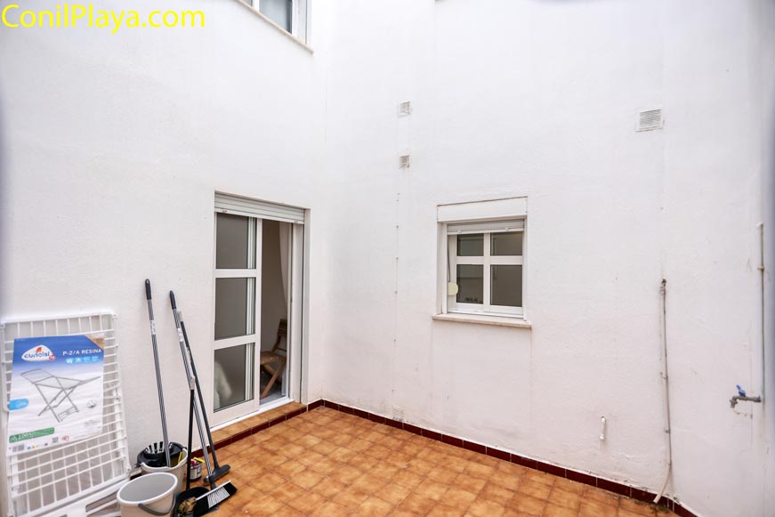 Patio interior privado con suelo de baldosa marrón y grifo, para guardar enseres playa