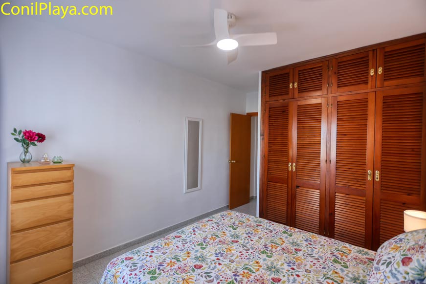 Dormitorio con armario empotrado de madera y ventilador de techo con luz