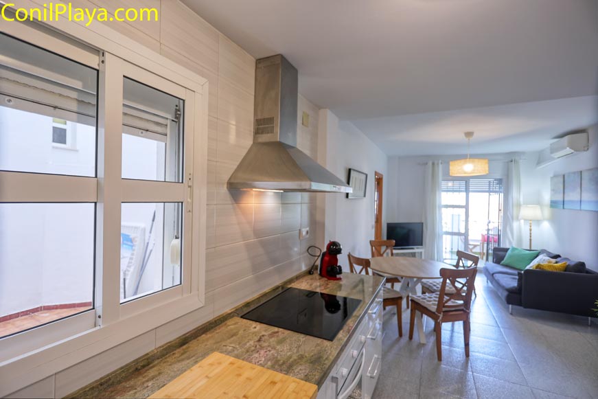 Cocina moderna con ventana al patio interior privado junto a salón comedor y mesa redonda