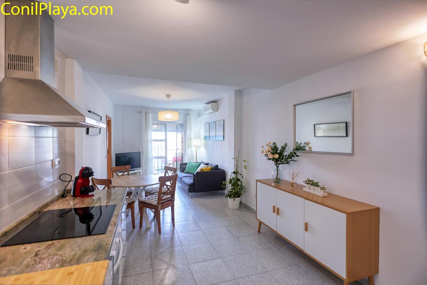 Salón con sofá, mesa comedor y aparador junto a la cocina