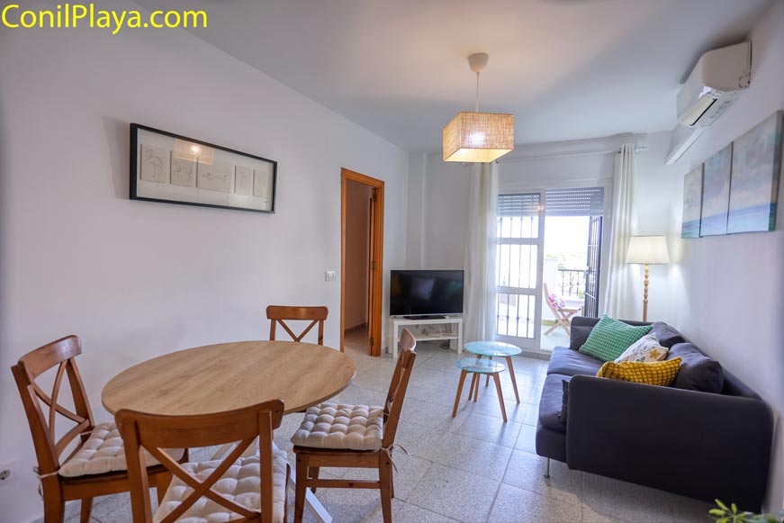 Salón con sofá, mesa redonda y aire acondicionado junto a ventana
