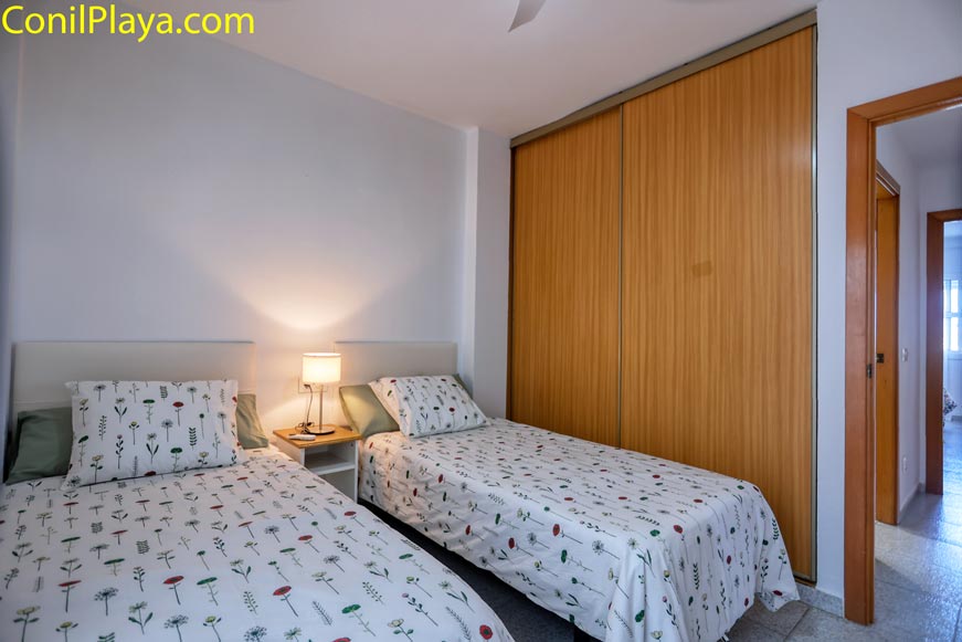 Dormitorio con dos camas individuales y armario empotrado junto a una lámpara