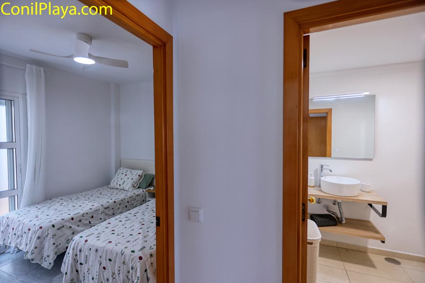 Vista desde el pasillo a dormitorio con dos camas y baño al fondo