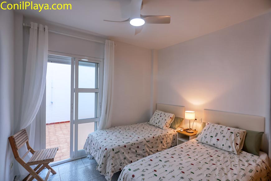 Dormitorio con dos camas individuales y ventilador en el techo