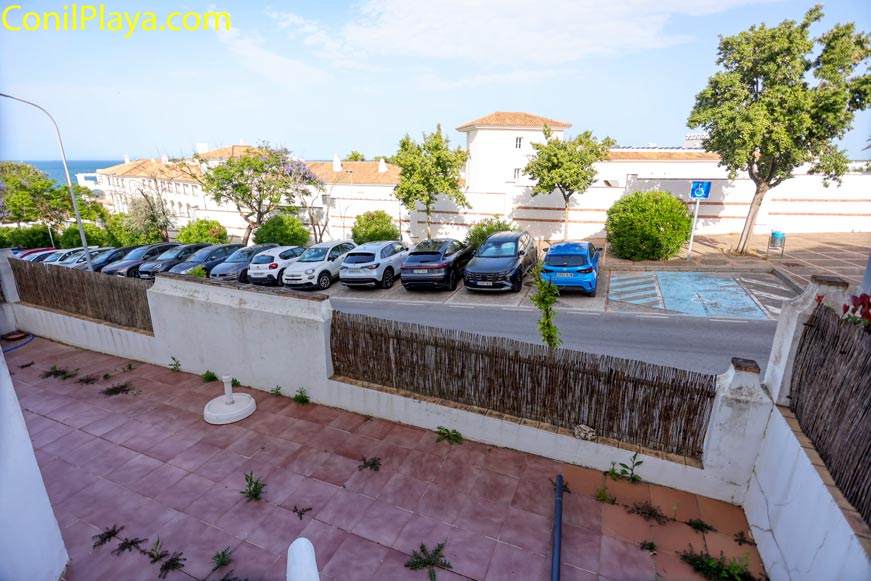 Fila de coches aparcados frente a patio exterior con murete bajo
