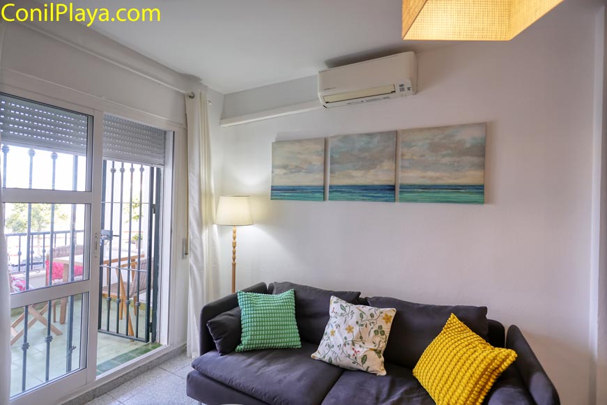 Salón con sofá y aire acondicionado junto a terraza acristalada