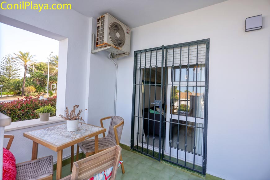 Terraza amueblada con mesa, sillas y plantas junto a ventana con reja