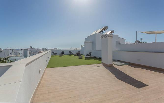 Amplia terraza en azotea con césped artificial y varias tumbonas