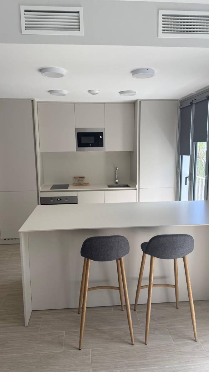 Cocina moderna con isla, taburetes altos y muebles minimalistas claros