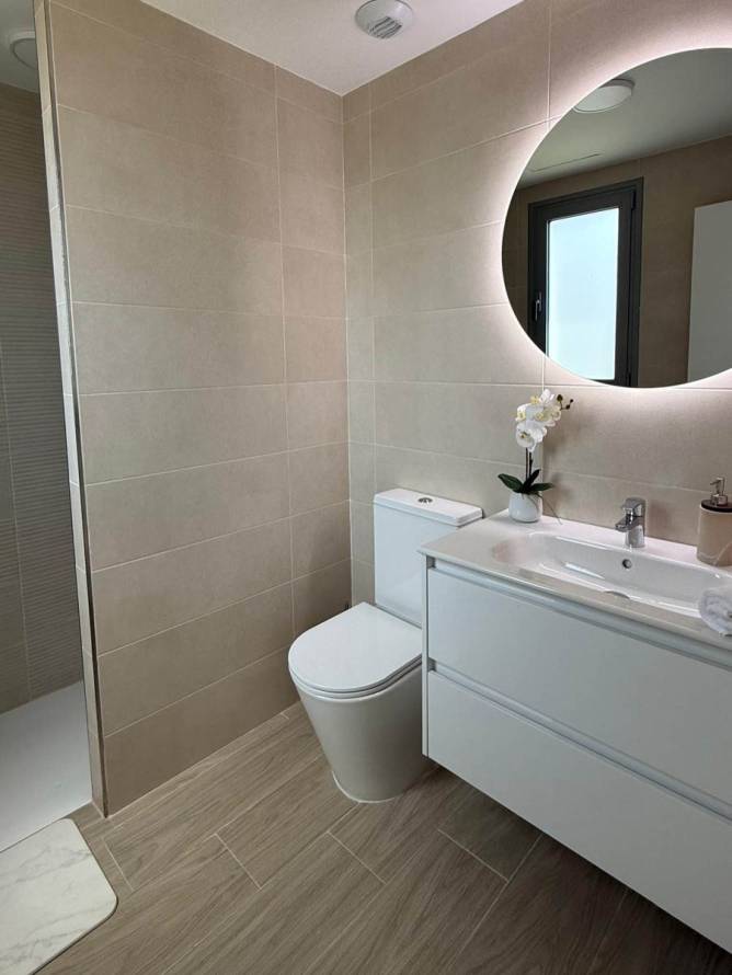 Cuarto de baño moderno con aseo y lavabo blanco visto desde la entrada