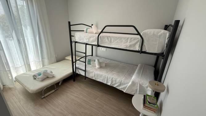 Dormitorio con literas, cama supletoria y mesa auxiliar junto a la ventana