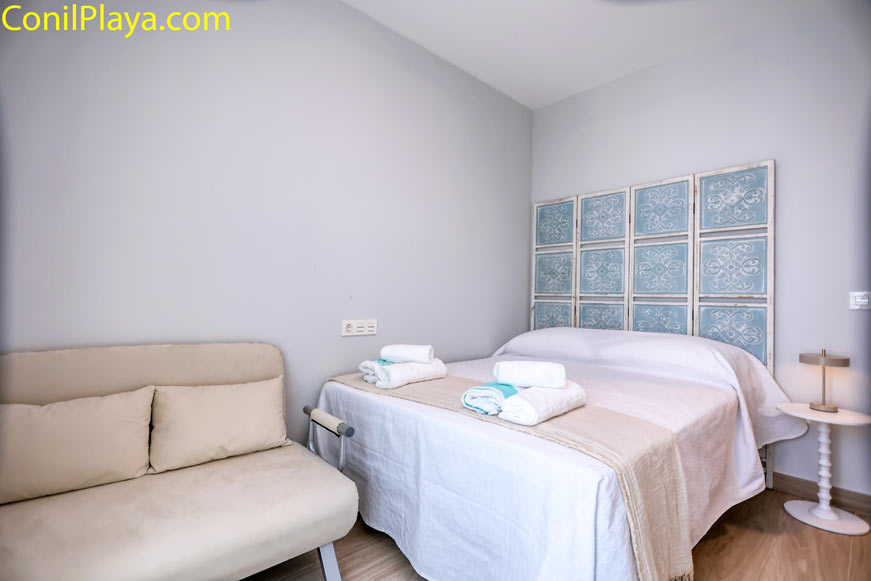Dormitorio con cama doble y sofá beige en espacio acogedor