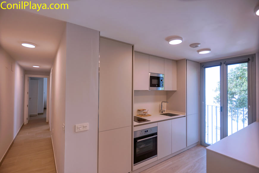 Cocina moderna y luminosa junto a un pasillo y puerta de balcón