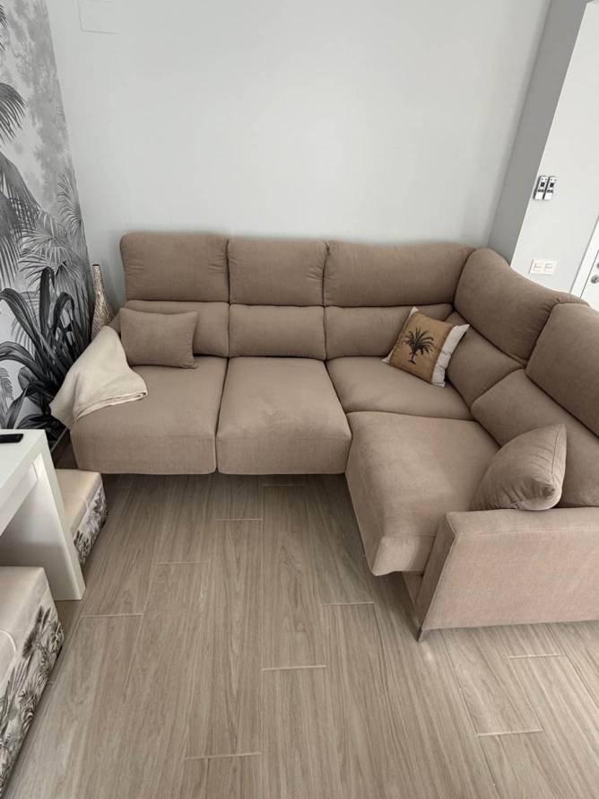 Sofa chaise longue beige en salón con suelo de madera clara