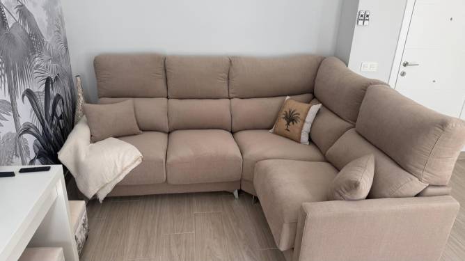 Sofa esquinero beige en salón moderno con cojines decorativos