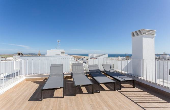 Terraza amplia con tumbonas de diseño vistas a edificios blancos cercanos