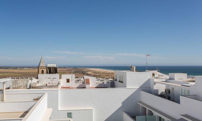 Vista desde azotea a edificios blancos y mar azul bajo cielo despejado en un día soleado