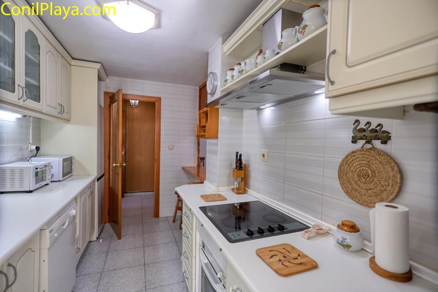 Cocina con placa vitrocerámica y horno Zona de cocción con placa vitrocerámica y horno integrado en el mobiliario.