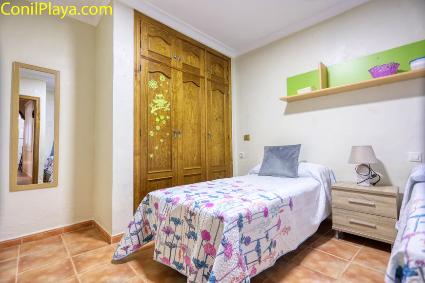 Dormitorio juvenil con dos camas individuales y armario de madera con detalles infantiles
