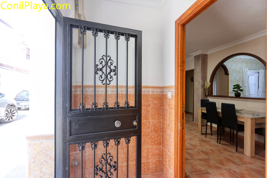 Recibidor interior con paredes de azulejo y acceso al salón