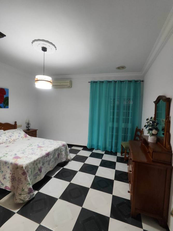 dormitorio con cama doble, aire acondicionado y cortinas turquesa
