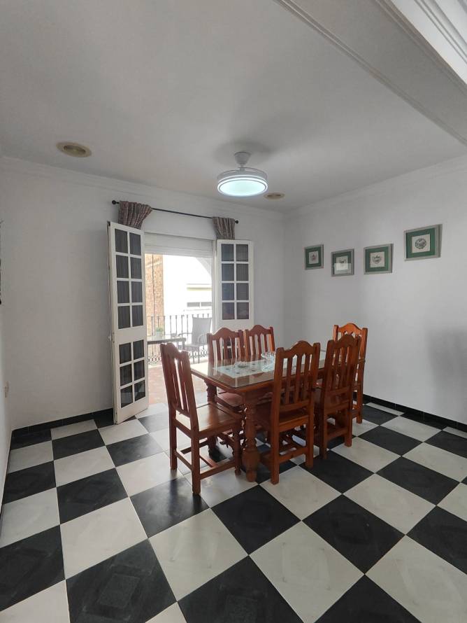 comedor con mesa de madera y sillas junto a puertas abiertas