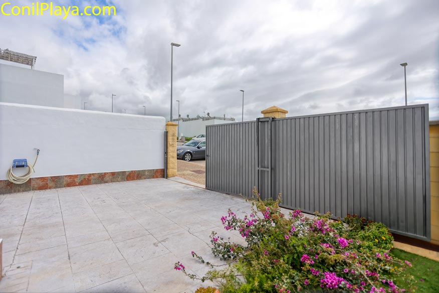 Patio privado con cancela metálica y plantas, aparcamiento en casa de alquiler en Conil.