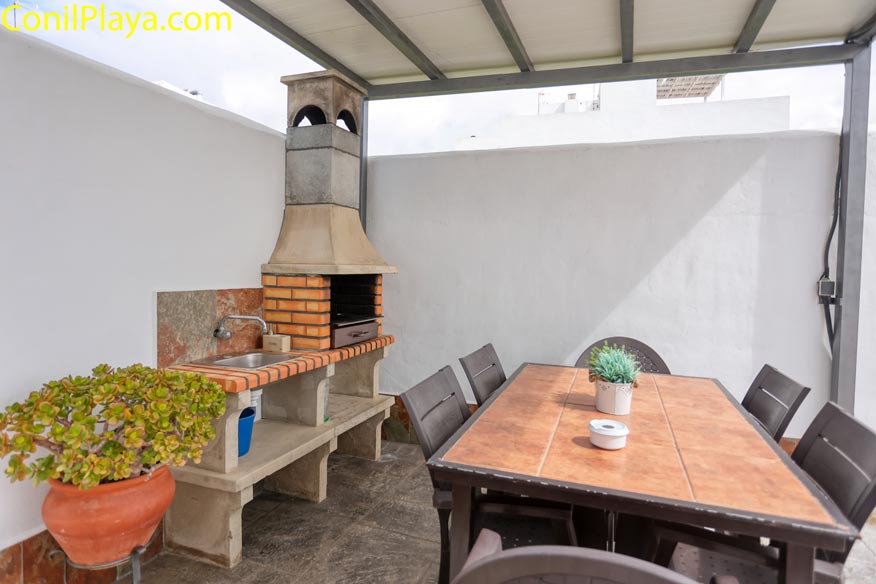 Primer plano de barbacoa de ladrillo y piedra con fregadero junto a mesa de comedor.