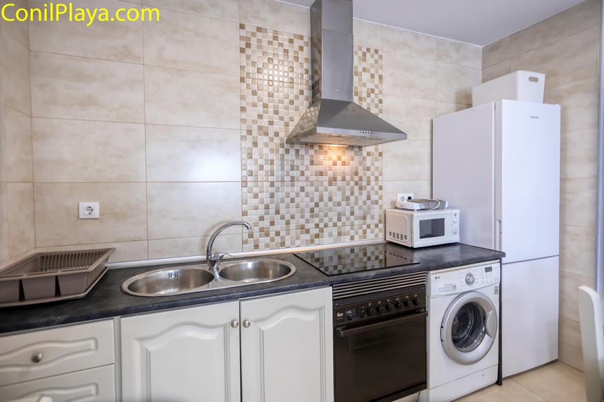 Cocina moderna con electrodomésticos, fregadero doble, horno, microondas y lavadora.