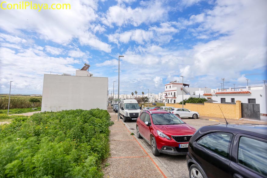 Calle residencial con aparcamientos y zonas verdes junto al alojamiento cerca de la playa.