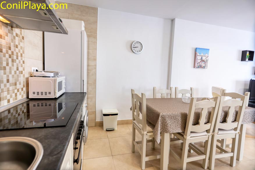 Mesa de comedor vestida con mantel beige y seis sillas de madera clara.