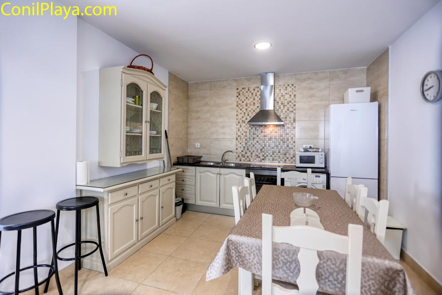 Mueble alacena clásico de color crema junto a la zona de comedor y taburetes.