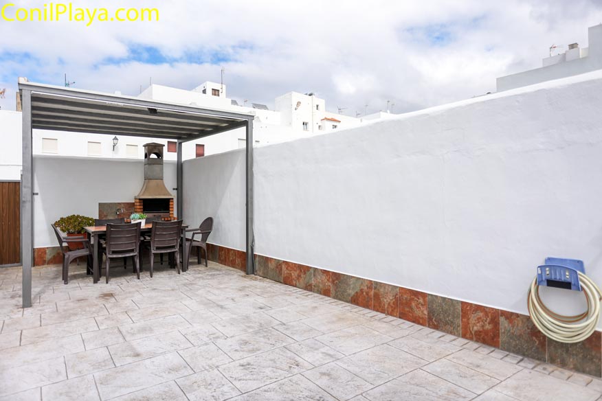 Patio con suelo de baldosa, mesa, sillas, barbacoa y pérgola metálica en terraza privada