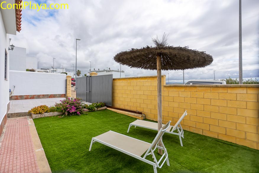 Perspectiva del jardín con césped artificial y buganvillas junto al muro.