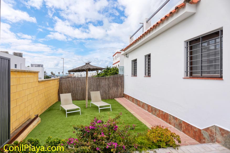 Zona de relax con tumbonas y sombrilla en casa en alquiler con aparcamiento en Conil.
