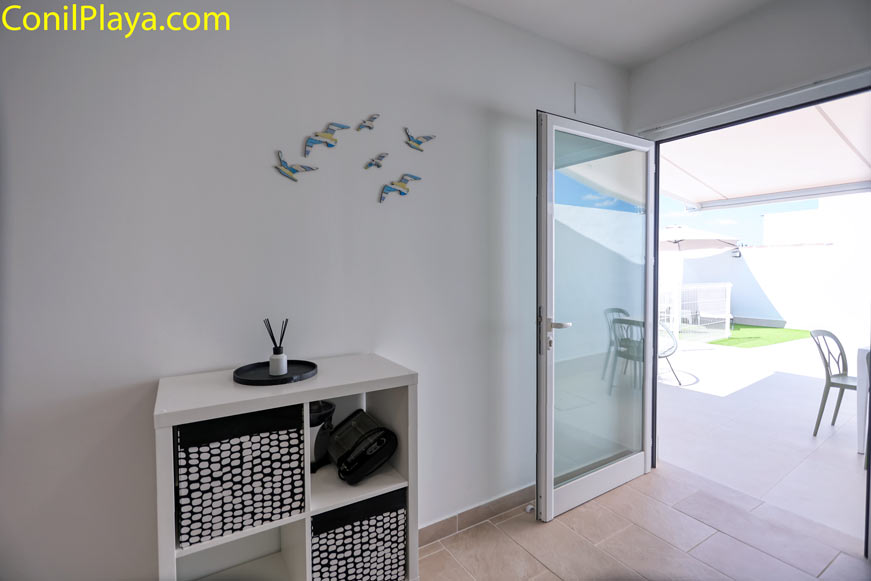 Mueble auxiliar blanco junto a la puerta acristalada de salida al patio