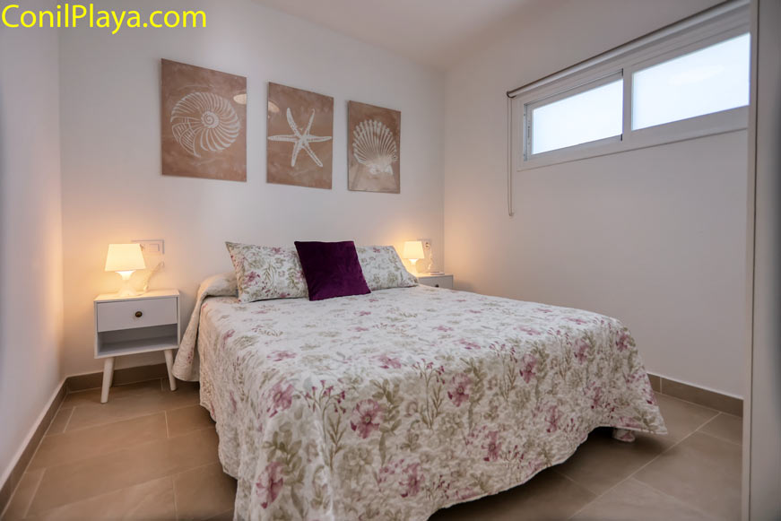 Dormitorio principal con cama de matrimonio, cuadros marinos y lámparas de noche