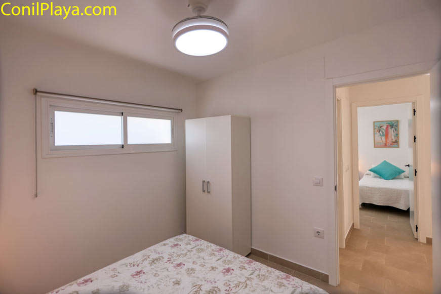 Habitación con armario blanco, ventilador de techo y ventana al exterior