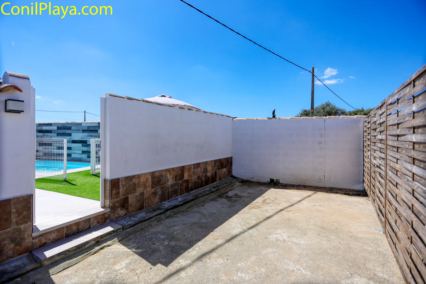 Zona aparcamiento, entrada y patio privado con muros blancos y valla de madera