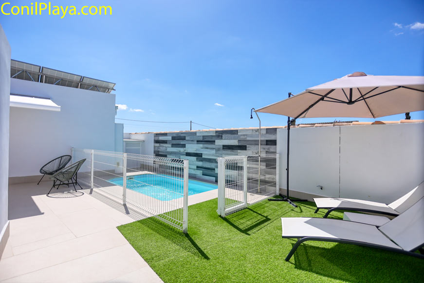 Piscina privada vallada para seguridad con zona de solárium y sillas