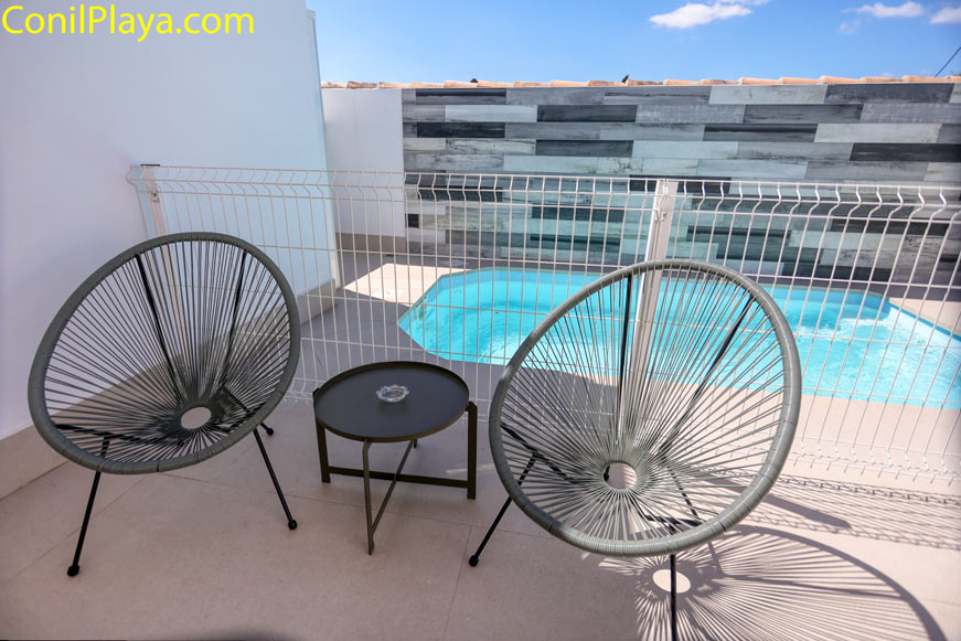 Par de sillas de diseño Acapulco con mesa auxiliar junto a la piscina