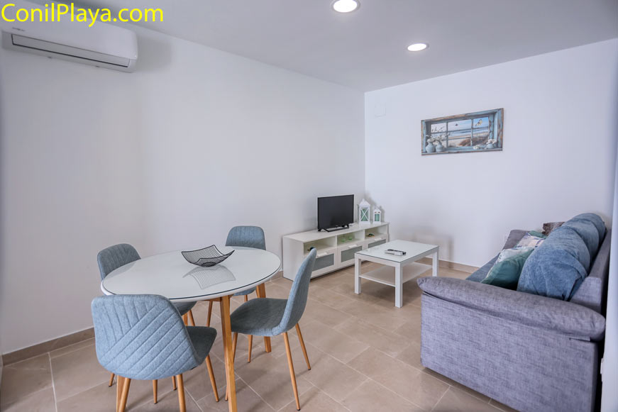 Comedor moderno con mesa redonda, sillas tapizadas y aire acondicionado