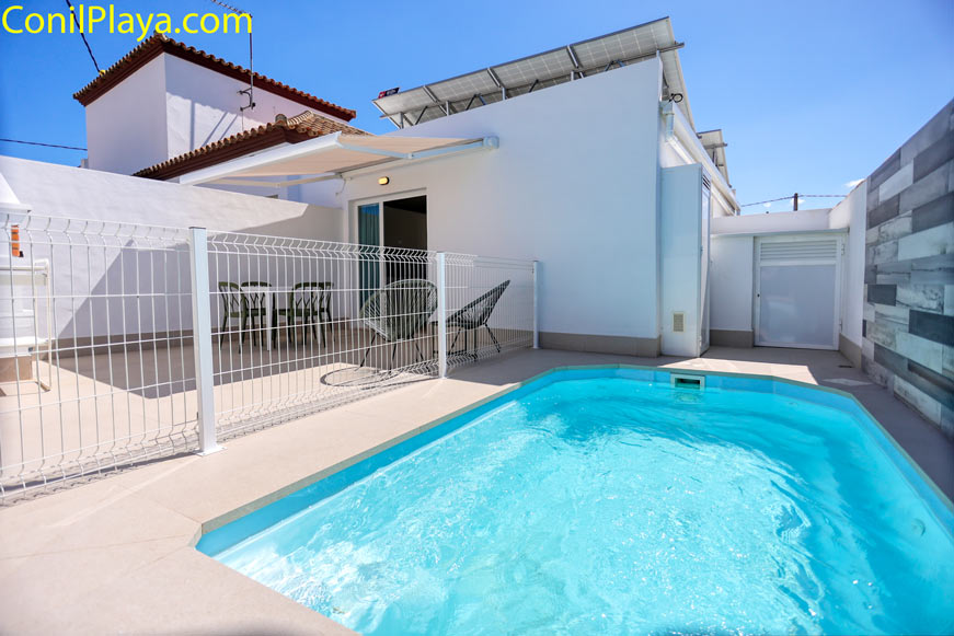 Fachada moderna con placas solares, toldo desplegado y piscina privada de la casa en Conil en alquiler
