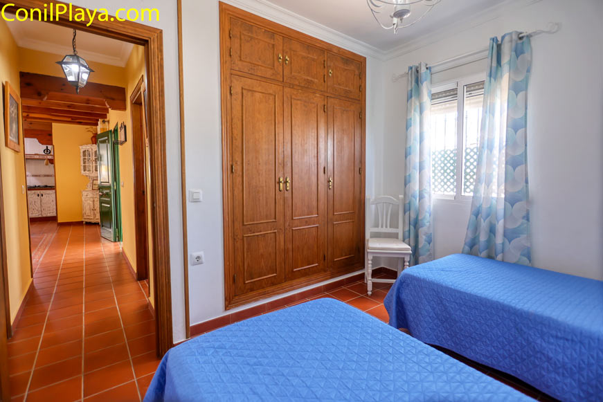 Dormitorio con dos camas, armario empotrado y ventana con cortinas azules