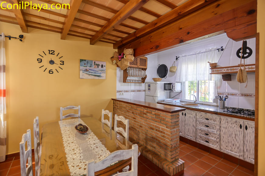 Comedor con mesa de madera junto a cocina rustica abierta y decoracion tradicional