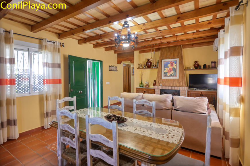 Comedor acogedor con mesa de madera y salón junto a chimenea y televisión