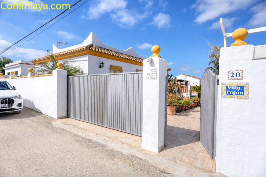 Entrada de aparcamiento con portón metálico junto a casa blanca
